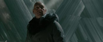 Movie still from “Superman Returns” (2006), directed by Bryan Singer – A bald man in a black jacket standing in the rain; Close Up shot, Low angle