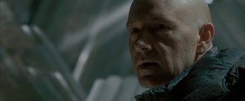 Movie still from “Superman Returns” (2006), directed by Bryan Singer – An older bald man is looking at the camera; Close Up shot, Over the shoulder angle