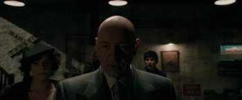 Movie still from “Superman Returns” (2006), directed by Bryan Singer – A man with a bald head in a suit and tie; Close Up shot, Over the shoulder angle