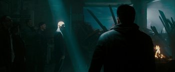 Movie still from “Superman Returns” (2006), directed by Bryan Singer – Two men are standing in a room with two large knifes in front of them; Wide shot, Over the shoulder angle