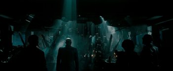 Movie still from “Superman Returns” (2006), directed by Bryan Singer – A man standing in the middle of a dark room; Wide shot, Low angle