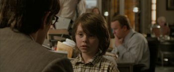 Movie still from “Superman Returns” (2006), directed by Bryan Singer – A young boy with long brown hair sitting at a table; Close Up shot, Over the shoulder angle