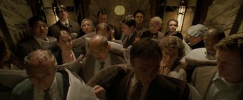 Movie still from “Superman Returns” (2006), directed by Bryan Singer – A group of people sitting in a room reading newspapers; Medium shot, High angle