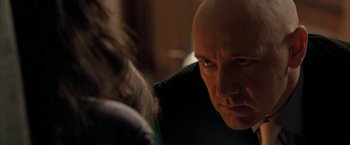 Movie still from “Superman Returns” (2006), directed by Bryan Singer – A bald man stares into the distance with his eyes wide open; Close Up shot, Over the shoulder angle