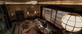 Movie still from “Superman Returns” (2006), directed by Bryan Singer – A man sitting at a desk in a room; Wide shot, High angle