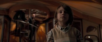 Movie still from “Superman Returns” (2006), directed by Bryan Singer – A little boy standing in a room with a guitar in the background; Medium shot, Low angle