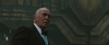 Movie still from “Superman Returns” (2006), directed by Bryan Singer – An older man wearing a suit and bow tie; Close Up shot, Low angle