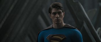 Movie still from “Superman Returns” (2006), directed by Bryan Singer – A man in a blue and black superman costume; Close Up shot, Over the shoulder angle