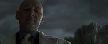 Movie still from “Superman Returns” (2006), directed by Bryan Singer – A bald man wearing a white jacket and a black tie; Close Up shot, Low angle