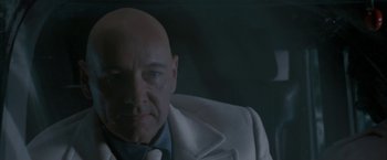 Movie still from “Superman Returns” (2006), directed by Bryan Singer – A man with bald head wearing a suit and tie; Close Up shot, Low angle