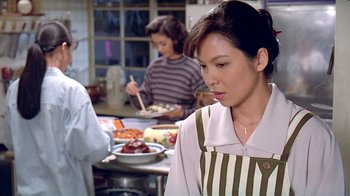Movie still from “Eat Drink Man Woman” (1994), directed by Ang Lee – A woman standing in front of a table of food in a kitchen; Close Up shot, High angle
