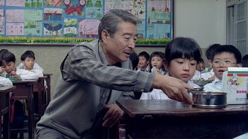 Movie still from “Eat Drink Man Woman” (1994), directed by Ang Lee – An older man teaching a young boy how to use an electric drill; Medium shot, Low angle