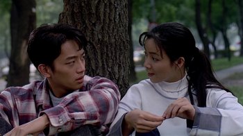 Movie still from “Eat Drink Man Woman” (1994), directed by Ang Lee – A man and a woman sitting next to a tree; Medium shot, Over the shoulder angle
