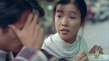 Movie still from “Eat Drink Man Woman” (1994), directed by Ang Lee – A young woman looking at a young man holding a cigarette; Close Up shot, Over the shoulder angle