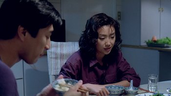 Movie still from “Eat Drink Man Woman” (1994), directed by Ang Lee – Two people sitting at a dinner table eating food; Medium shot, Over the shoulder angle