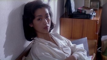 Movie still from “Eat Drink Man Woman” (1994), directed by Ang Lee – A woman sitting on top of a bed wearing a white shirt; Close Up shot, High angle
