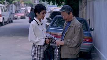 Movie still from “Eat Drink Man Woman” (1994), directed by Ang Lee – An older man and a young woman standing on a sidewalk; Medium shot, High angle