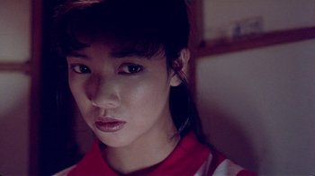 Movie still from “Eat Drink Man Woman” (1994), directed by Ang Lee – A young asian woman in a red and white shirt looking at the camera; Close Up shot, High angle