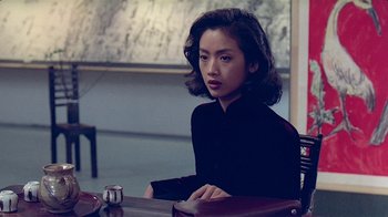 Movie still from “Eat Drink Man Woman” (1994), directed by Ang Lee – A woman sitting at a table in front of a coffee mug; Medium shot, Over the shoulder angle