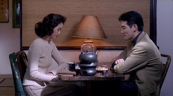 Movie still from “Eat Drink Man Woman” (1994), directed by Ang Lee – A man and a woman sitting at a table with a tea pot on it; Medium shot, High angle