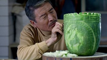 Movie still from “Eat Drink Man Woman” (1994), directed by Ang Lee – An older man touching his face while looking at a green object; Close Up shot, Over the shoulder angle