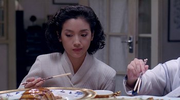 Movie still from “Eat Drink Man Woman” (1994), directed by Ang Lee – A woman sitting at a table with chopsticks in front of a plate of food; Close Up shot, Over the shoulder angle