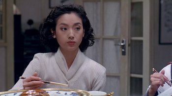 Movie still from “Eat Drink Man Woman” (1994), directed by Ang Lee – A woman sitting at a table with a plate in front of her; Close Up shot, Over the shoulder angle