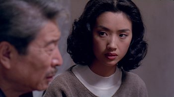 Movie still from “Eat Drink Man Woman” (1994), directed by Ang Lee – An asian woman in a brown and white sweater looks at an older man in a white shirt; Close Up shot, Over the shoulder angle