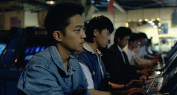 Movie still from “Rebels of the Neon God” (1992), directed by Tsai Ming-liang – A group of young men sitting next to each other in a room; Medium shot, High angle