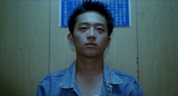 Movie still from “Rebels of the Neon God” (1992), directed by Tsai Ming-liang – A young man with spiky black hair is looking at the camera; Close Up shot, Low angle