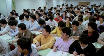 Movie still from “Rebels of the Neon God” (1992), directed by Tsai Ming-liang – A group of people sitting in a room with papers on the tables; Wide shot, High angle