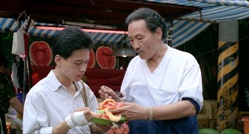 Movie still from “Rebels of the Neon God” (1992), directed by Tsai Ming-liang – An older man and a young man are eating watermelon; Medium shot, Over the shoulder angle