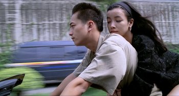 Movie still from “Rebels of the Neon God” (1992), directed by Tsai Ming-liang – A man and a woman riding a bike down a street; Medium shot, High angle
