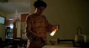 Movie still from “Rebels of the Neon God” (1992), directed by Tsai Ming-liang – A person holding a candle in a room; Medium shot, Low angle