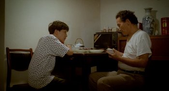 Movie still from “Rebels of the Neon God” (1992), directed by Tsai Ming-liang – Two people sitting at a dinner table looking at their cell phones; Medium shot, High angle