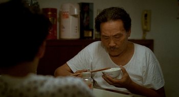 Movie still from “Rebels of the Neon God” (1992), directed by Tsai Ming-liang – A man sitting at a table with chopsticks in a bowl; Close Up shot, High angle