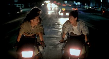 Movie still from “Rebels of the Neon God” (1992), directed by Tsai Ming-liang – A group of people riding motorcycles down a street at night; Medium shot, High angle