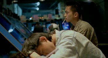 Movie still from “Rebels of the Neon God” (1992), directed by Tsai Ming-liang – A man sleeping on the ground with a cigarette in his mouth; Medium shot, High angle