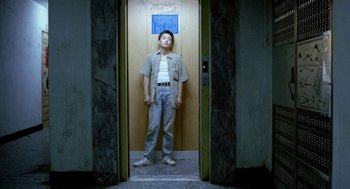 Movie still from “Rebels of the Neon God” (1992), directed by Tsai Ming-liang – A man standing in an elevator with his hands on his hips; Wide shot, Low angle