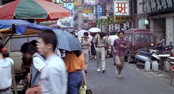 Movie still from “Rebels of the Neon God” (1992), directed by Tsai Ming-liang – A group of people walking down a street under an umbrella; Wide shot, High angle