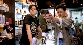 Movie still from “Rebels of the Neon God” (1992), directed by Tsai Ming-liang – A man is taking a picture of another man holding a cell phone; Medium shot, Low angle