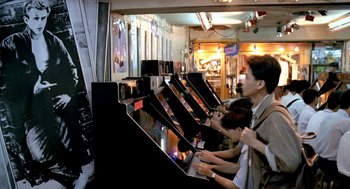 Movie still from “Rebels of the Neon God” (1992), directed by Tsai Ming-liang – A group of people playing a video arcade game together; Wide shot, High angle