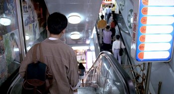 Movie still from “Rebels of the Neon God” (1992), directed by Tsai Ming-liang – A group of people walking up and down an escalator; Wide shot, Overhead angle