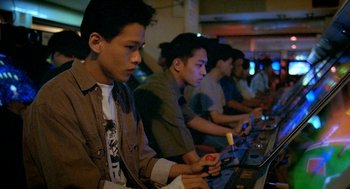 Movie still from “Rebels of the Neon God” (1992), directed by Tsai Ming-liang – A group of young men playing a video game; Medium shot, High angle