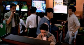 Movie still from “Rebels of the Neon God” (1992), directed by Tsai Ming-liang – A group of people playing a video game together; Wide shot, High angle