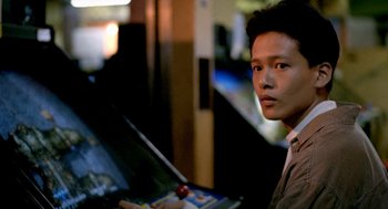 Movie still from “Rebels of the Neon God” (1992), directed by Tsai Ming-liang – A man sitting in front of a laptop computer; Close Up shot, Over the shoulder angle