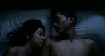 Movie still from “Rebels of the Neon God” (1992), directed by Tsai Ming-liang – A man and a woman sleeping in a bed together; Medium shot, Overhead angle
