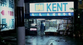 Movie still from “Rebels of the Neon God” (1992), directed by Tsai Ming-liang – A man standing in front of a store on a rainy day; Extreme Wide shot, High angle
