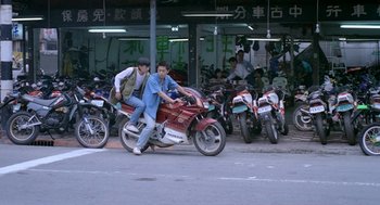 Movie still from “Rebels of the Neon God” (1992), directed by Tsai Ming-liang – Two young men are riding a motorcycle in a parking lot; Wide shot, High angle