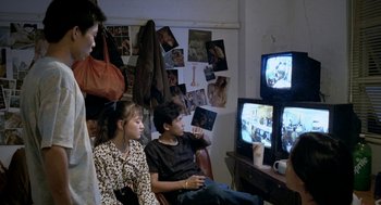 Movie still from “Rebels of the Neon God” (1992), directed by Tsai Ming-liang – A group of people sitting in front of a television; Medium shot, High angle